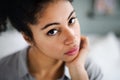 Close-up portrait of sad beautiful young woman indoors, looking at camera. Royalty Free Stock Photo