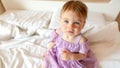 Close up portrait of sad blue-eyed toddler. Baby looks to the camera sitting on the bed. Royalty Free Stock Photo