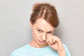 Portrait of sad tearful girl with white drops of face cream on skin