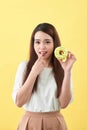 Close up portrait of a satisfied pretty girl eating donuts over yellow background