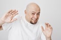 Close-up portrait of scared bald bearded man raising hands to cover from something, squinting as if looking at sunlight Royalty Free Stock Photo