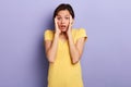 Close-up portrait of scared cute emotional charming girl with palms on cheeks