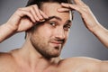 Close up portrait of a scared shirtless man plucking eyebrows