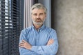 Close-up portrait of a senior businessman standing in the office with his arms crossed on his chest, confidently and Royalty Free Stock Photo