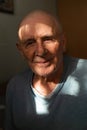 Close-up portrait of senior caucasian man at home in sunlight pocket. Retirement alone, loneliness of old man.