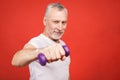 Close-up portrait Of A Senior Man Exercising with dumbbells against red Background Royalty Free Stock Photo