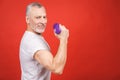 Close-up portrait Of A Senior Man Exercising with dumbbells against red Background Royalty Free Stock Photo