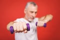 Close-up portrait Of A Senior Man Exercising with dumbbells against red Background Royalty Free Stock Photo