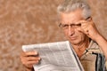 Close-up portrait of senior man reading newspaper on a beige background Royalty Free Stock Photo