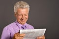 Close-up portrait of senior man reading newspaper on gray Royalty Free Stock Photo