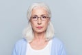 Close up portrait of serious, aged, charming woman in glasses over grey background