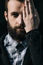 Close-up portrait of a serious bearded man with closed eye over black background Royalty Free Stock Photo