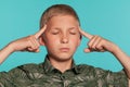 Close-up portrait of a blonde teenage boy in a green shirt with palm print posing against a blue studio background Royalty Free Stock Photo