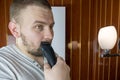 Close up portrait of a serious man shaving beard with an electric razor Royalty Free Stock Photo