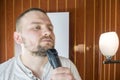 Close up portrait of a serious man shaving beard with an electric razor Royalty Free Stock Photo