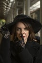 Close-up portrait of serious middle-aged woman in black clothes wears hat with veil and lace gloves. Aristocrat in mourning Royalty Free Stock Photo