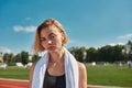 Close up portrait of serious sporty young woman with towel around her neck looking at camera while posing on the track Royalty Free Stock Photo