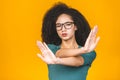 Close up portrait of a serious young african american woman showing stop or no gesture with her palm isolated over yellow Royalty Free Stock Photo