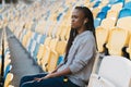 Close-up portrait of the serious young afro-american girl observing the match while sitting on the seats of the stadium. Royalty Free Stock Photo