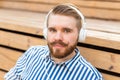 Close-up portrait of a serious young student guy listening to his favorite online radio using headphones while sitting Royalty Free Stock Photo