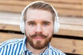 Close-up portrait of a serious young student guy listening to his favorite online radio using headphones while sitting Royalty Free Stock Photo