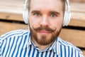 Close-up portrait of a serious young student guy listening to his favorite online radio using headphones while sitting Royalty Free Stock Photo