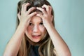 Close-up portrait of shocked unhappy little girl with long hair holding her head in hands Royalty Free Stock Photo