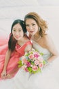 Asian bride and bridesmaid sitting on bed Royalty Free Stock Photo