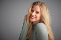 Portrait of blond young woman looking at camera and smiling while posing at light grey background Royalty Free Stock Photo