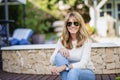 Attractive and happy woman wearing sunglasses and casual clothes while relaxing at the backyard at home Royalty Free Stock Photo