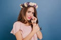 Close-up portrait of shy white girl in flower wreath posing on blue background. Indoor photo of dark-haired lady with Royalty Free Stock Photo