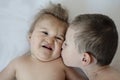Close-up portrait of siblings lying on bed. Older boy kisses his disabled younger brother on cheek
