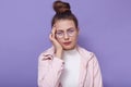 Close up portrait of sick attractive cute young female, standing isolated over lilac background in studio, putting fingers on