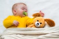 Close-up portrait of a sleeping baby in an embrace with a toy and a pacifier in his mouth Royalty Free Stock Photo