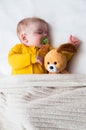 Close-up portrait of a sleeping baby in an embrace with a toy and a pacifier in his mouth. Vertical photo Royalty Free Stock Photo