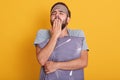 Close up portrait of sleepy young man with his pillow in hands, yawning and covering his mouth with palms, posing with blindfold Royalty Free Stock Photo