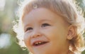 Close up portrait of a small blond baby boy. Funny kids cropped face outdoor on sunny day. Kids smiling, cute smile. Royalty Free Stock Photo