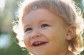 Close up portrait of a small blond baby boy. Funny kids cropped face outdoor on sunny day. Kids smiling, cute smile. Royalty Free Stock Photo