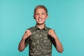 Close-up portrait of a blonde teenage boy in a green shirt with palm print posing against a blue studio background Royalty Free Stock Photo