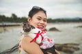 Close up portrait Smiley young Asian woman in a sweet dress standing and holding an adorable cat on her shoulder on the beach in