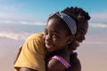 Close-up portrait of smiling african american girl embracing young father against sea and sky Royalty Free Stock Photo