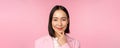 Close up portrait of smiling asian working lady in suit, businesswoman looking thoughtful, thinking or deciding smth