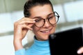 Close-up portrait of smiling beautiful woman in office touching her eyeglasses, wearing blue turtleneck, reading good news on her Royalty Free Stock Photo