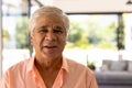 Close-up portrait of smiling biracial senior man against windows in nursing home