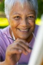 Close-up portrait of smiling biracial senior woman painting with paintbrush on canvas in yard