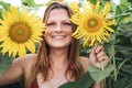 Close up portrait of smiling blond woman holding yellow flowers in sunflower field Royalty Free Stock Photo