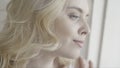 Close up portrait of a smiling blond woman looking outside through window. Action. Beautiful young girl with curly hair Royalty Free Stock Photo