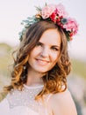 The close-up portrait of the smiling bride with the wreath of flowers on the head.