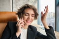 Close up portrait of smiling brunette woman, businesswoman talking on mobile phone, making a call and smiling, sitting Royalty Free Stock Photo