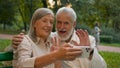 Close up portrait smiling Caucasian middle aged retired family couple talking relaxing using smartphone outdoors city Royalty Free Stock Photo